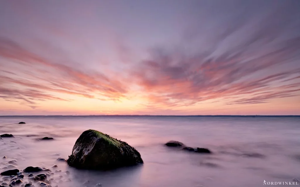 sehr lange belichtungszeit miclhiges wasser am strand zum sonnenuntergang