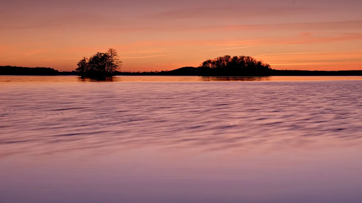 minimalismus fotografie durch brennweite zweier inseln zum sonnenuntergang im see