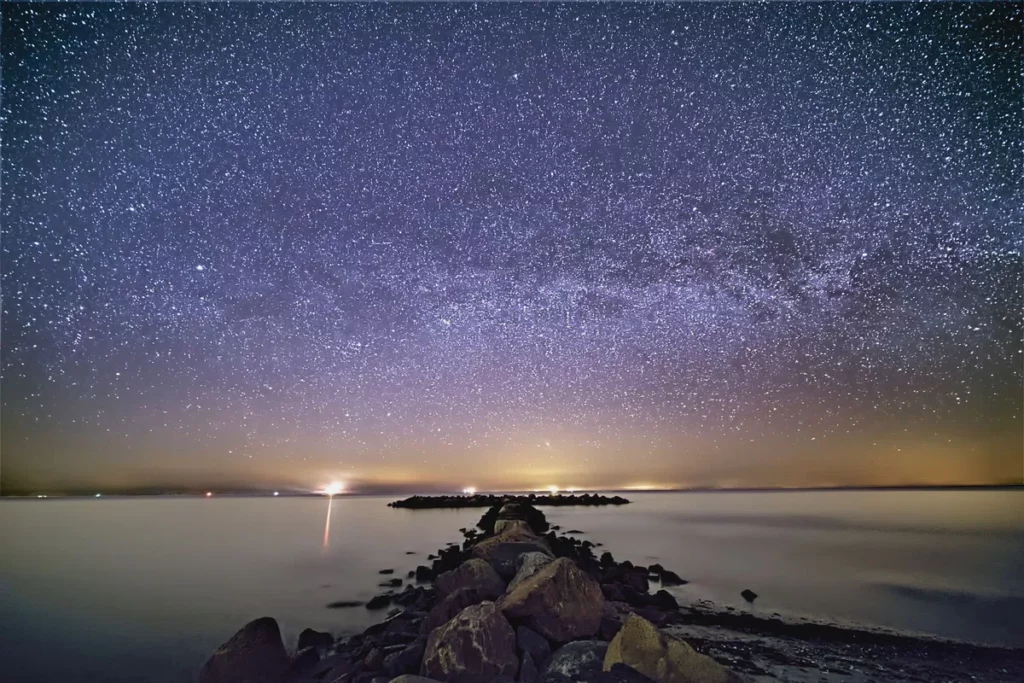 milchstraße über wellenbrecher am strand mit hoher lichtempfindlichkeit fotografiert