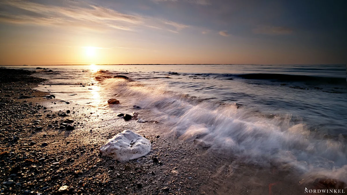 welle rauscht verschwommen an den Strand zum sonnenuntergang