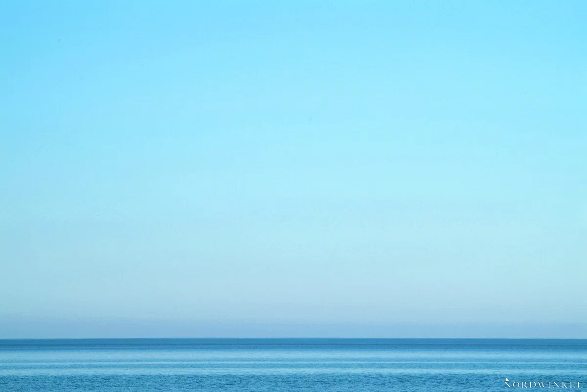 minimalistisches bild der ostsee mit türkisfarbenem himmel und einem kleinen streifen meer
