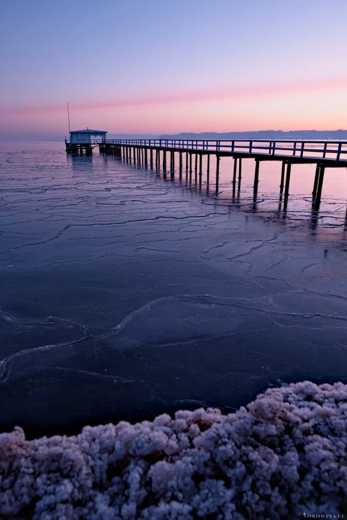 seebrücke in kiel mit vereister ostsee zum sonnenaufgang