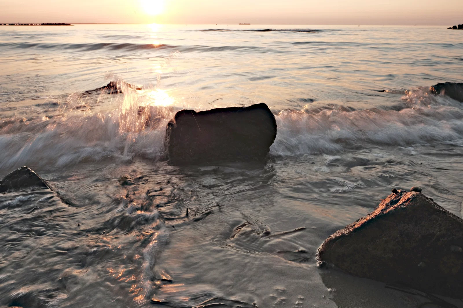 jpeg bild einer welle am steinstrand zum sonnenuntergang aufgehellt