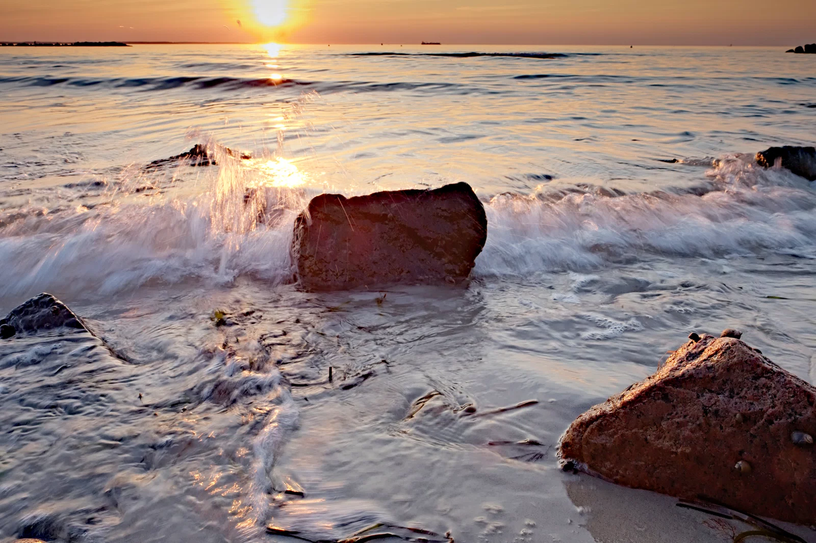 raw bild einer welle am steinstrand zum sonnenuntergang aufgehellt