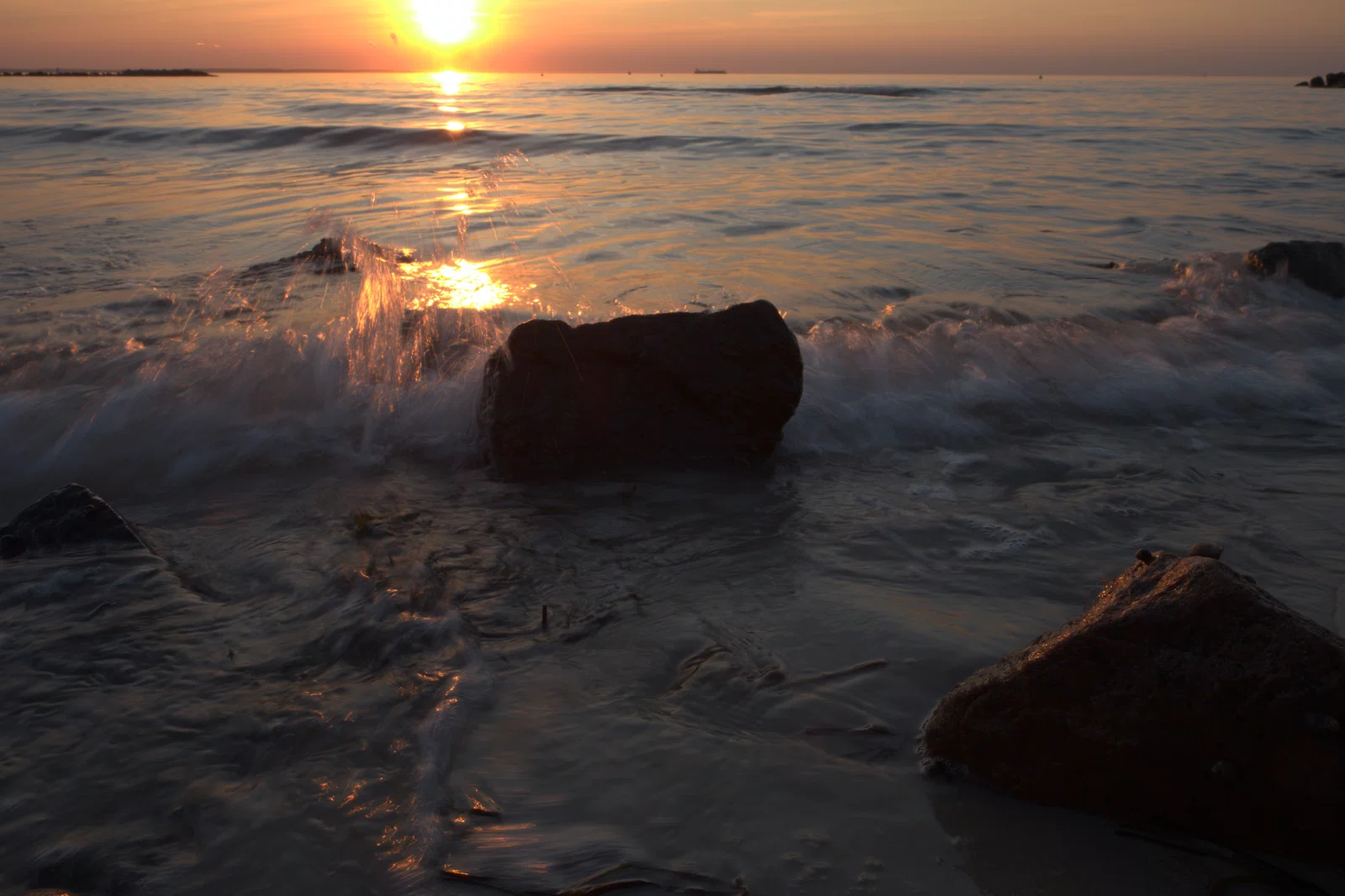 raw bild einer welle am steinstrand zum sonnenuntergang 