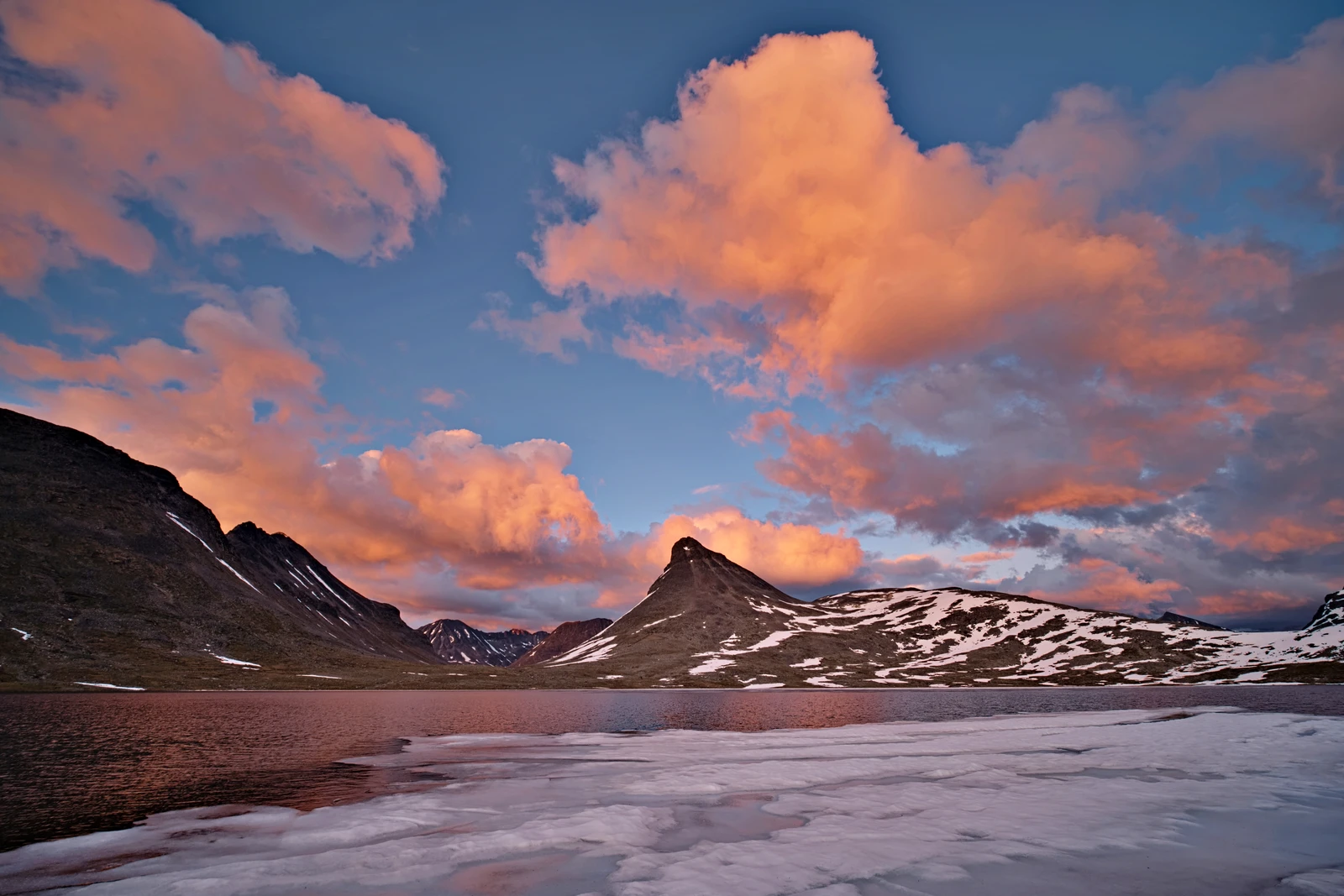 fototrick farbkontraste mit blauem himmel orangenen wolken über schneebedeckten bergen