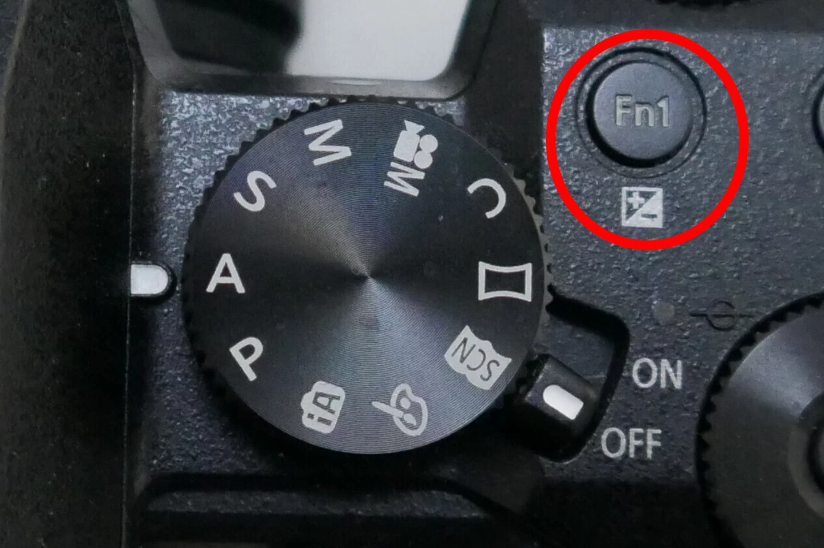 markierter knopf auf einer kamera mit dem symbol der belichtungskorrektur