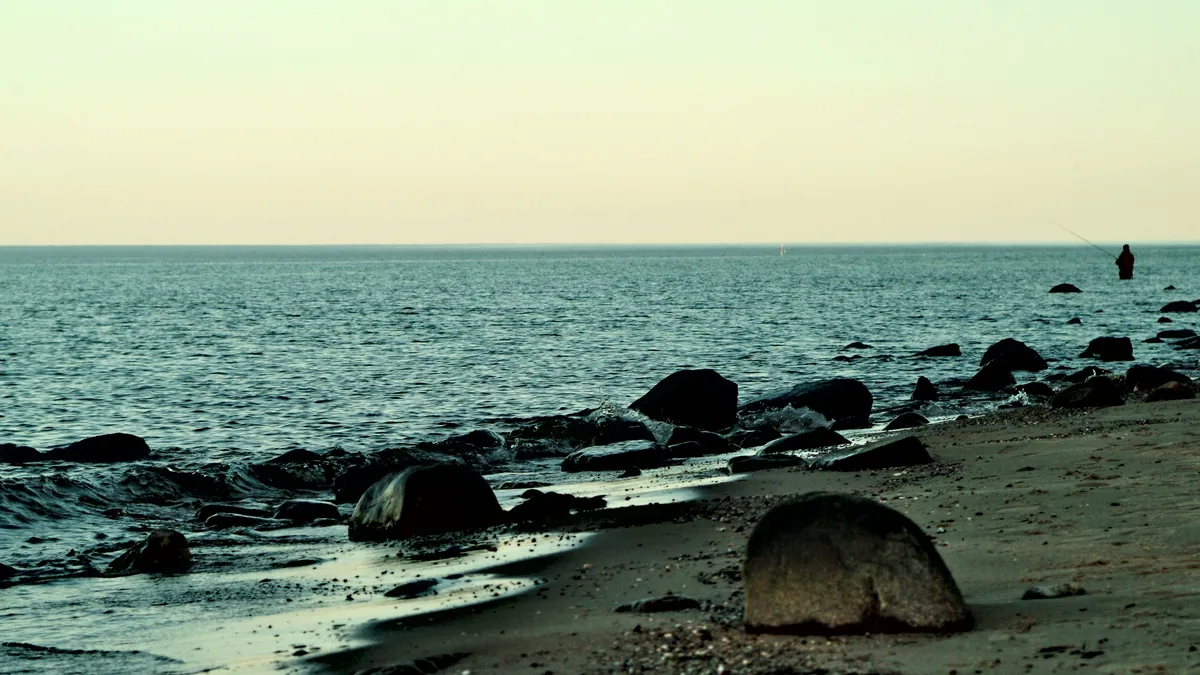 angler in der ostsee am strand bei sonnenuntergang mit pastellfarben