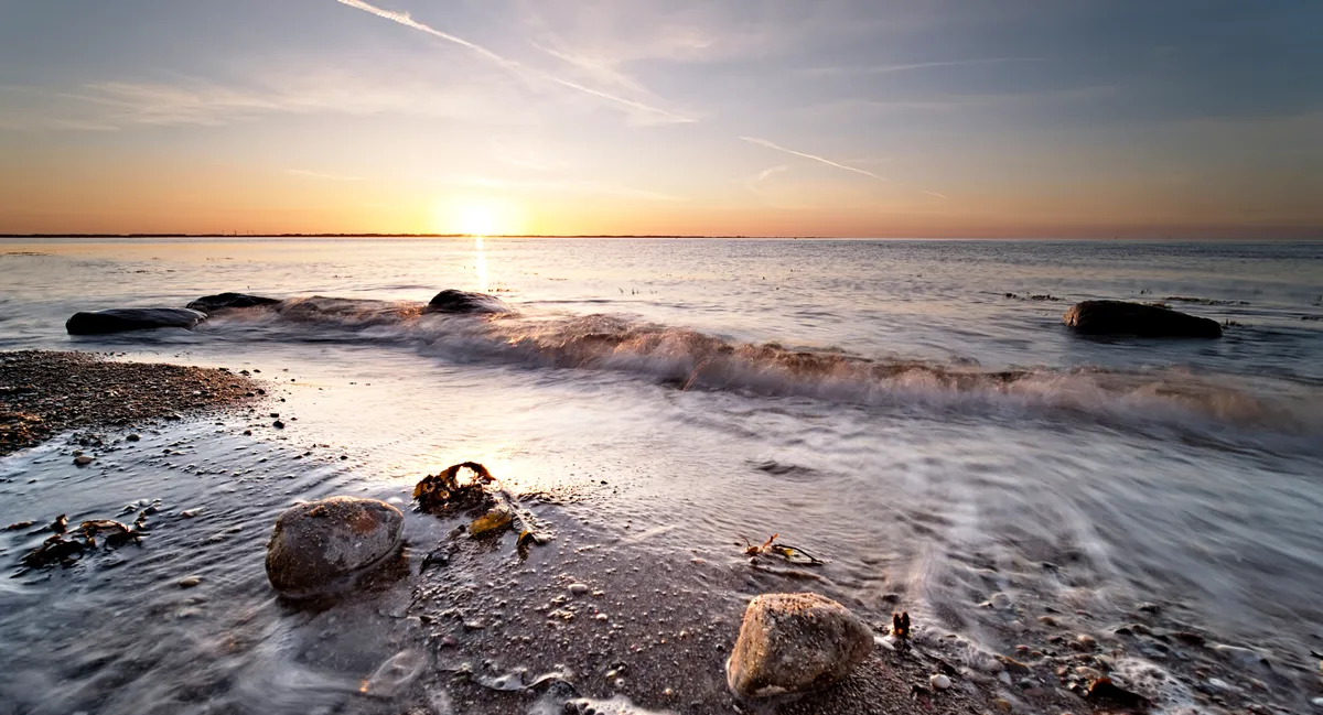 sonnenuntergang ostseestrand mit brechender welle