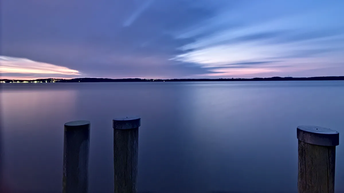 sonnenaufgang am see mit drei buhnen im vordergrund