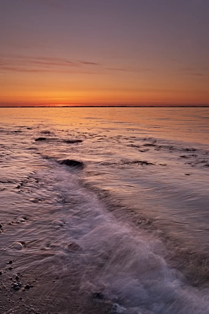 sonnenuntergang an der ostsee bei wolkenlosem himmel im hochformat