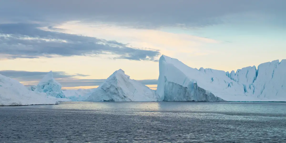 riesige eisberge unter pastell leuchtendem himmel mit dunklen wolken